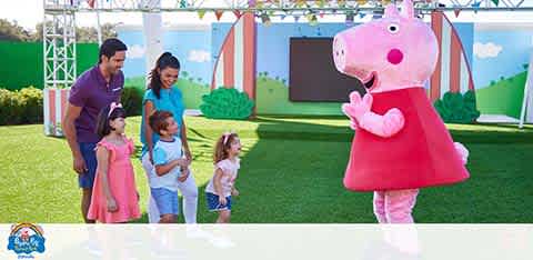 Family with kids meeting a large pink cartoon character outdoors.