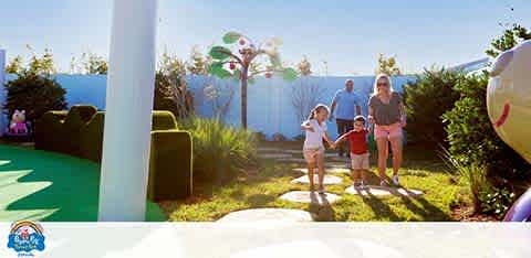 Family walking in a sunny theme park with whimsical decor.