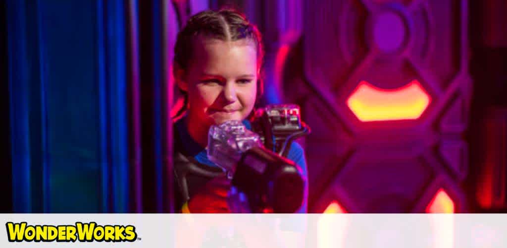 Child plays laser tag, neon lights in background. "WonderWorks" logo visible.