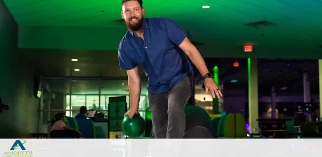 A man smiles as he prepares to bowl at an indoor bowling alley.