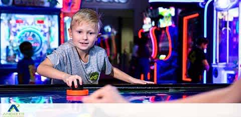 A boy plays air hockey in a vibrant arcade setting.