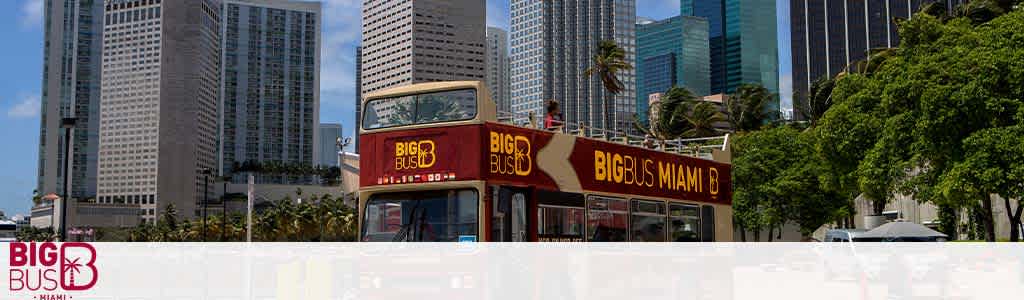 Big Bus Miami tour bus with open top, in front of high-rise buildings.