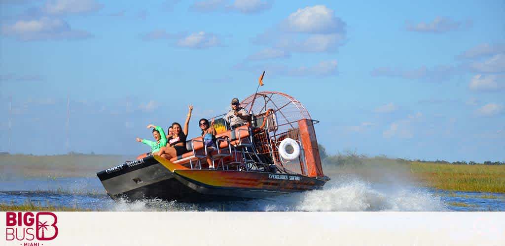 Airboat with passengers gliding over water, with "BIG BUS Miami" logo, sunny sky.