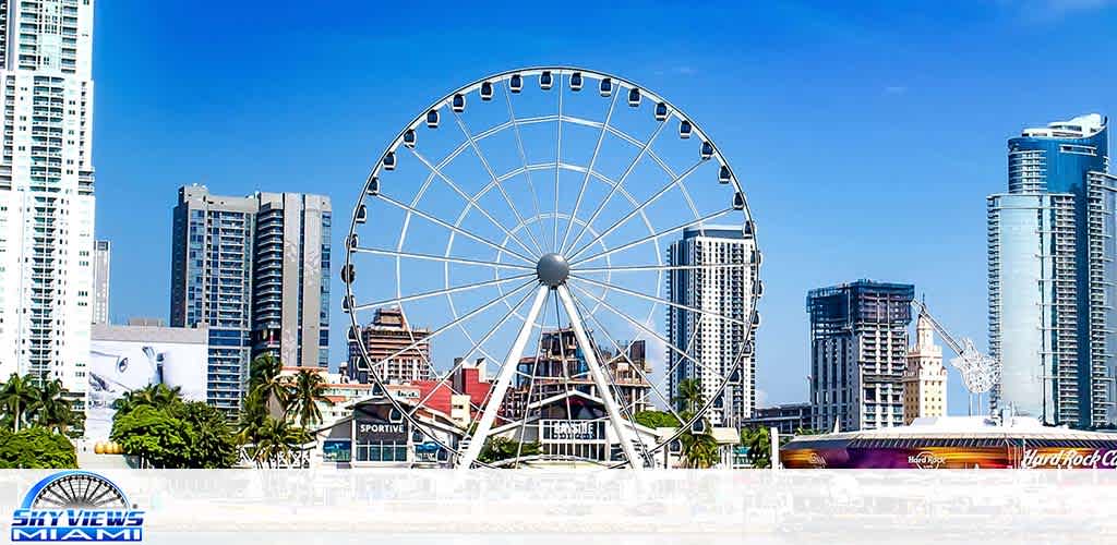 Ferris wheel by waterfront amidst high-rises under blue sky.