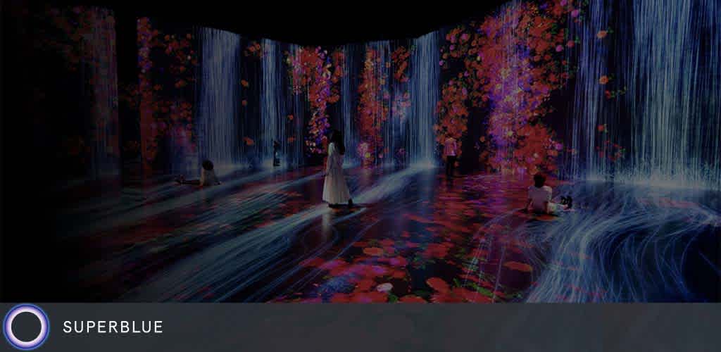 A room with people and flowing digital projections of water and flowers on the walls.