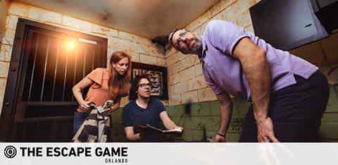 Three individuals collaborate in a room with a prison-like window, seemingly in an escape room game.