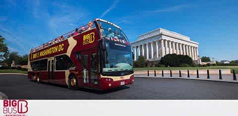 A red double-decker tour bus labeled 'Big Bus Washington DC' is on a road in front of the iconic Lincoln Memorial under a clear blue sky. The bus has an open top deck and a full lower deck with visible branding and promotional text.