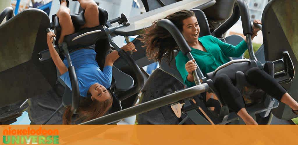 Visitors enjoy a thrilling ride at Nickelodeon Universe, with their feet dangling as their seats rotate in the air. Excited expressions reflect the amusement and adventure of the park experience.