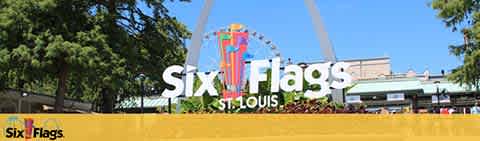 Image shows a sunny day at Six Flags St. Louis. A large, colorful sign with the park's name is in the foreground. Behind it, green trees and a clear blue sky frame park structures and a Ferris wheel, capturing the excitement of this amusement destination.