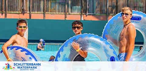 Three individuals at Schlitterbahn Waterpark in Galveston, Texas, are holding blue transparent tubes, preparing for water activities. They're standing by a pool, wearing swimsuits and sunglasses, with a look of anticipation for the fun ahead. The sun is shining brightly on a day perfect for waterpark adventures.