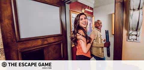 Image of two excited individuals, a woman on the left and a man on the right, exiting a room with smiles indicating a successful escape room experience. The Escape Game logo is visible at the image's bottom indicating the venue.