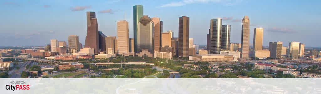 Image of Houston skyline with various skyscrapers under a clear sky during daylight. Trees and smaller buildings are visible in the foreground. The text 'Houston CityPASS' is overlaid in the upper left corner.