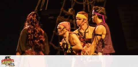 Four actors on stage in a theatrical production with a pirate theme, under warm lighting.