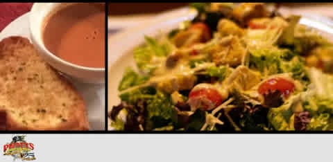 Bowl of soup with bread and a fresh green salad with tomatoes on a table.