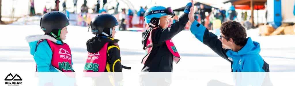 This image captures a cheerful moment at a ski resort, presumably taken during the day under a clear sky. Three young ski students, all equipped with protective helmets, are lined up on the left side of the image, facing right. Their helmets are black, and each wears a bright, neon-colored vest—one in cyan with 'BIG BEAR KIDS' and another in yellow, red, and black with the same logo. The third student's vest is obscured from view. The individual student on the far right extends their left hand for a high-five to an instructor, who is wearing a blue jacket. The instructor is leaning in to return the gesture, a symbol of encouragement or celebration. The scene suggests they are either starting a lesson or celebrating the completion of one. In the backdrop, there's a glimpse of a snowy mountain base with other ski enthusiasts and some infrastructure, like ski lifts and buildings.

At FunEx.com, we take pride in offering not just unforgettable experiences, but also the chance to lock in the lowest prices and significant savings on tickets, ensuring that your adventure doesn’t break the bank.