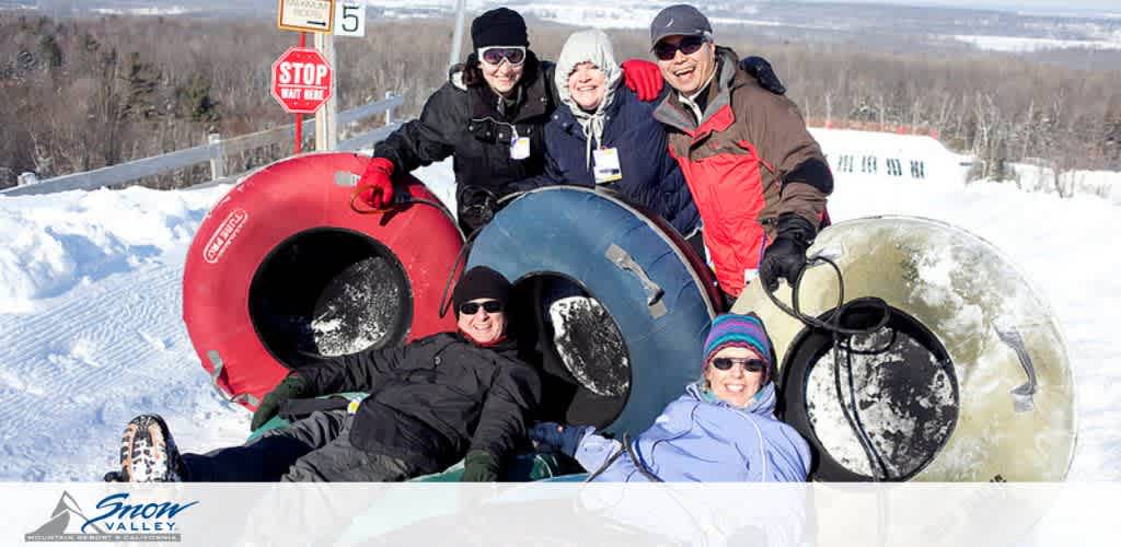 Image description: A group of joyful people are seen outdoors during a winter day at a tubing park named Snow Valley. All are wearing warm winter clothing, including jackets, hats, and gloves, to protect against the cold weather. Four individuals are seated on the snow, each with a large tube suitable for snow tubing. The tubes come in various colors, including red, blue, black, and yellow. Behind the seated individuals, two more individuals are standing, appearing to be assisting or joining the group. Everyone is smiling and posing for the camera, conveying a sense of fun and excitement. In the background, we see a clear sky, a white snow-covered landscape with trees, and a stop sign indicating a tubing lane number. On the bottom left corner, the logo of Snow Valley is visible, enhancing the branding of the location.

Join us for an exhilarating experience on the snow slides and enjoy the thrill of winter fun at its best. Don't forget to check out FunEx.com for the lowest prices and great savings on tickets to exciting destinations like Snow Valley!