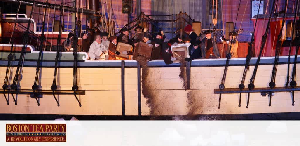 Image of a historical reenactment at the Boston Tea Party Ships and Museum. Actors in period costume are seen throwing crates from a ship's deck into the water, reenacting the famous 1773 protest. The scene is set at dusk with the ship illuminated by ambient light, and a sign in the foreground promotes the experience as 'A Revolutionary Experience'.