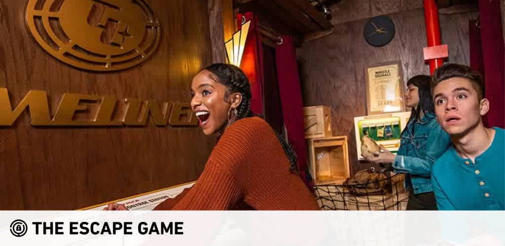 Image Description: This image captures an exciting moment at "The Escape Game." Two individuals are prominently featured in the foreground, both expressing a mixture of surprise and enjoyment. On the left, a woman with her mouth open in an animated laugh or shout wears a rust-colored sweater. Next to her, a young man with wide eyes and a startled expression looks towards something off-camera. They are in a room with a wooden wall to the right, and a section of the wall painted in a deep red behind them. Various props and décor suggest a thematic puzzle-solving environment. In the background, another person appears focused on an element of the game. Above the group, the large, bold logo "THE ESCAPE GAME" is displayed on the wall.

For even more excitement, visit FunEx.com where you can find the lowest prices and greatest savings on tickets for a variety of fun experiences such as The Escape Game.