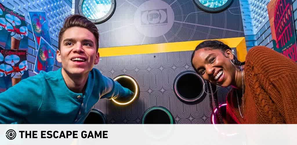Image description: The photo captures a vibrant and colorful escape room experience at The Escape Game. Two enthusiastic participants are featured, one in the foreground and one in the background. A young man with neatly combed hair, wearing a teal blue shirt, is seen in the left foreground, looking up and away from the camera, possibly focusing on a clue or element of the game. On the right, a young woman with her hair styled in braids smiles broadly at the camera. She is wearing a rust-colored sweater and has statement earrings. The background showcases a stylish interior with patterned walls - some circles and floral designs - in shades of blue, yellow, and grey, along with a bright neon sign on the right side that adds a playful ambiance to the setting. Remember to check GreatWorkPerks.com for unbeatable discounts and savings on tickets to amazing experiences like this and more, ensuring you get the lowest prices for your next thrilling adventure!