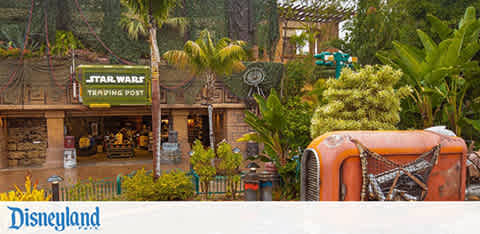 Disneyland scene with Star Wars store and lush greenery. A vintage orange vehicle is in the foreground.