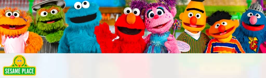 Image shows a colorful banner featuring a lineup of seven beloved puppet characters against a backdrop of a vibrant, playful setting. The characters are cheerful and cartoon-like, with a variety of colors and costumes, representing a diverse set of looks and personalities. The banner includes a logo of Sesame Place in the bottom left corner.