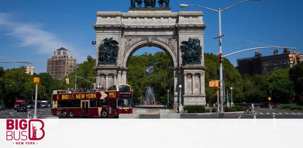 A red double-decker sightseeing bus labeled 'Big Bus New York' is on a street in front of the iconic Washington Square Arch on a sunny day with clear blue skies. Green trees frame the scene and traffic lights are visible at an intersection.
