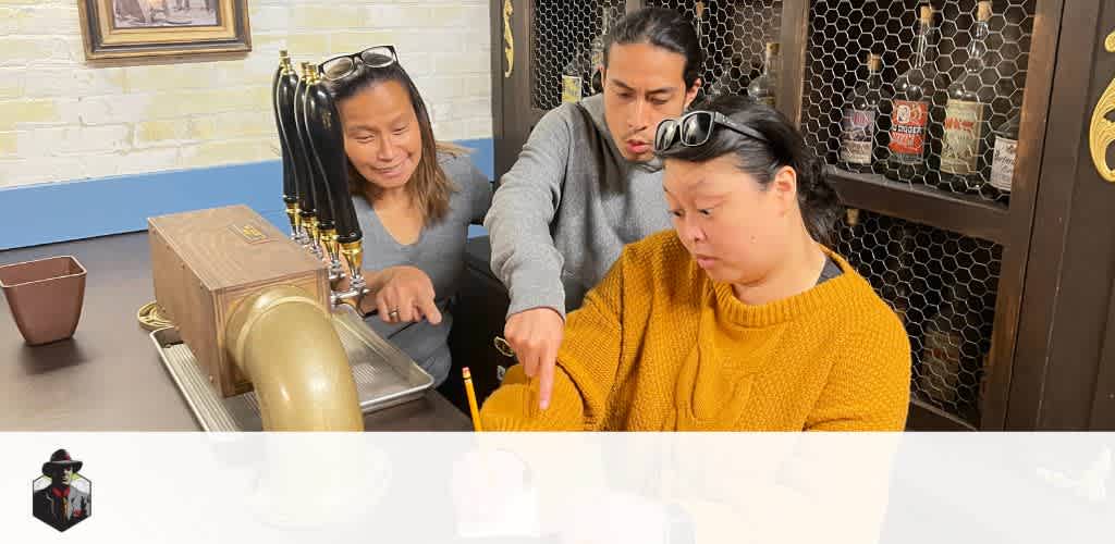 This image features three individuals working together in an indoor environment that resembles a bar or an escape room designed to replicate a bar setting. On the left, a person wearing a gray long-sleeve shirt smiles while observing something on the table in front of her. In the center, an individual with a gray hoodie appears focused as they lean over to examine an element on the table more closely. On the right, a person wearing a mustard-colored chunky knitted sweater is intently engaged in an activity with what appears to be a clue or a puzzle component at the center of the table. Above the group, traditional style taps affixed to a beer dispenser suggest a theme related to a tavern or brewery. The décor includes wooden accents and shelves lined with bottles behind a chicken wire safety barrier, creating an immersive, possibly puzzle-solving adventure atmosphere.

At GreatWorkPerks.com, we're committed to not just unlocking the mysteries in escape rooms but also unlocking the best deals for you—expect significant savings as you access the lowest prices on tickets for your next fun-filled adventure!