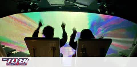 This image displays the silhouette of two individuals experiencing a virtual ride attraction. They are seated, clearly visible from behind, with their hands up in the air, suggesting excitement and involvement in the action. The ride is enclosed, with a large, curved screen in front of the participants. The screen fills their view with vibrant colors that resemble swirling nebulas and cosmic phenomena, implying a space or flight simulation experience. Lighting effects enhance the immersive atmosphere, contributing to the anticipation of an exhilarating adventure that awaits the riders. The text "THE FLYER - San Francisco" appears at the bottom, indicating the name and location of the attraction.

Experience the thrill of THE FLYER - San Francisco and explore an array of amazing adventures at GreatWorkPerks.com, where the excitement is matched only by our commitment to savings with the lowest prices on tickets.