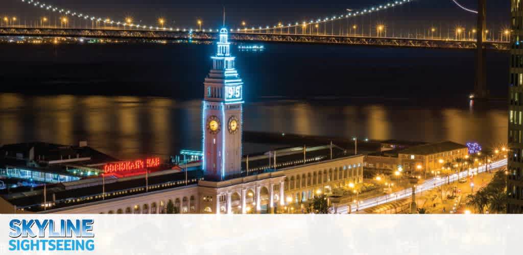 Night view of a lit clock tower with a bridge in the background.