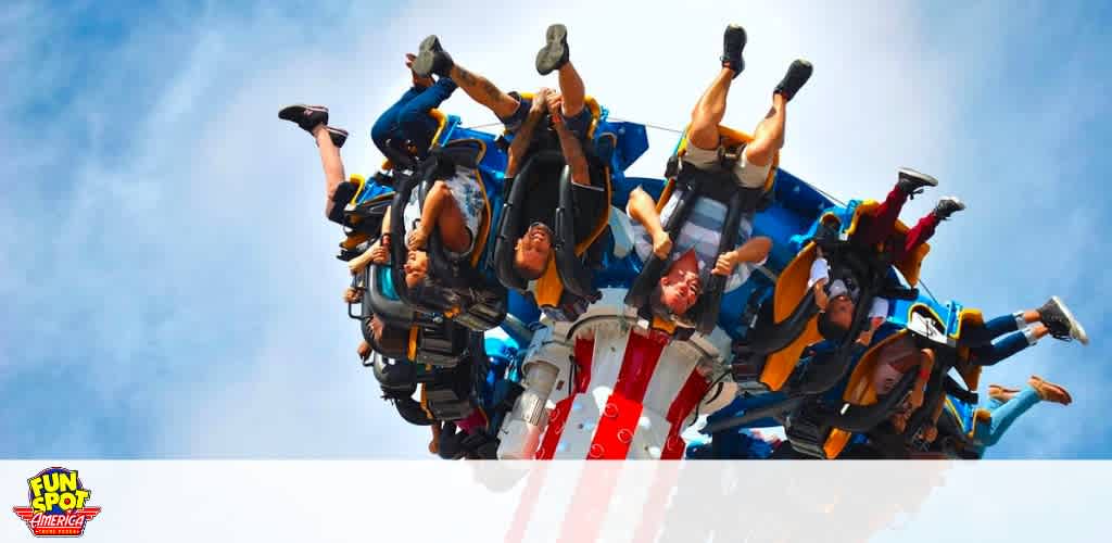 People on an upside-down roller coaster against a clear blue sky.