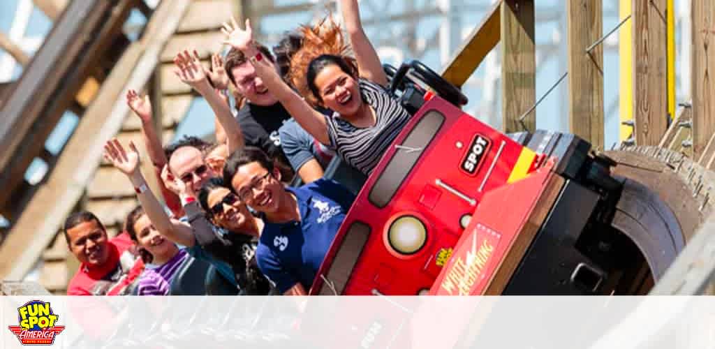 Thrilled riders on a roller coaster with hands raised, enjoying the ride at Fun Spot America.