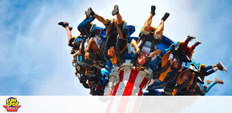 Thrill-seekers upside down on a roller coaster against a blue sky.