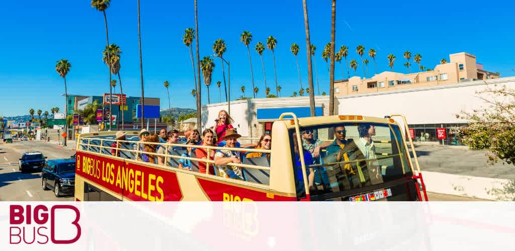 Tourists on an open-top Big Bus in bright daylight, palm trees lining the street.