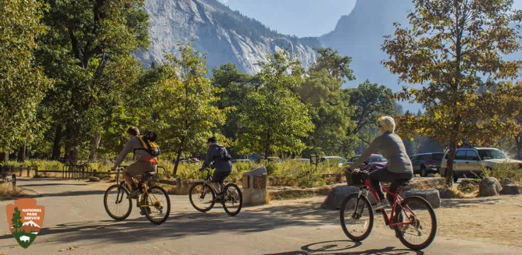 Three cyclists enjoy a ride in a scenic park with mountains in the background.