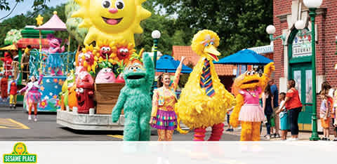 "Sesame Street characters in a sunny parade with happy visitors watching."