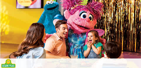 Family enjoys a moment with colorful Sesame Street characters in a festive setting.