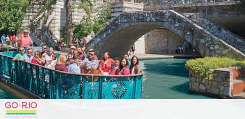 A cheerful group of people leans on a turquiose railing along a river, with a stone bridge in the background. Bright vegetation adorns the bridge and the riverbank. The sky is clear and sunny. Text on the image reads 'GO-RIO'.