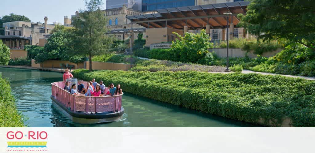 A vibrant river scene with a group of passengers enjoying a boat tour. Lush greenery lines the riverbank under a clear sky. Modern architecture is visible in the background, suggesting an urban setting. The boat, marked with 'GO RIO,' glides gently on the calm waters.