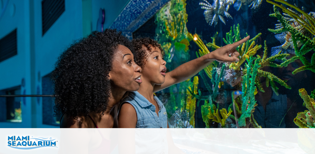 Woman and child excitedly pointing at fish in an aquarium.