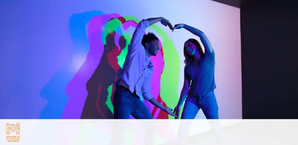 Two people form a heart shape with their arms against a wall with colorful shadows.