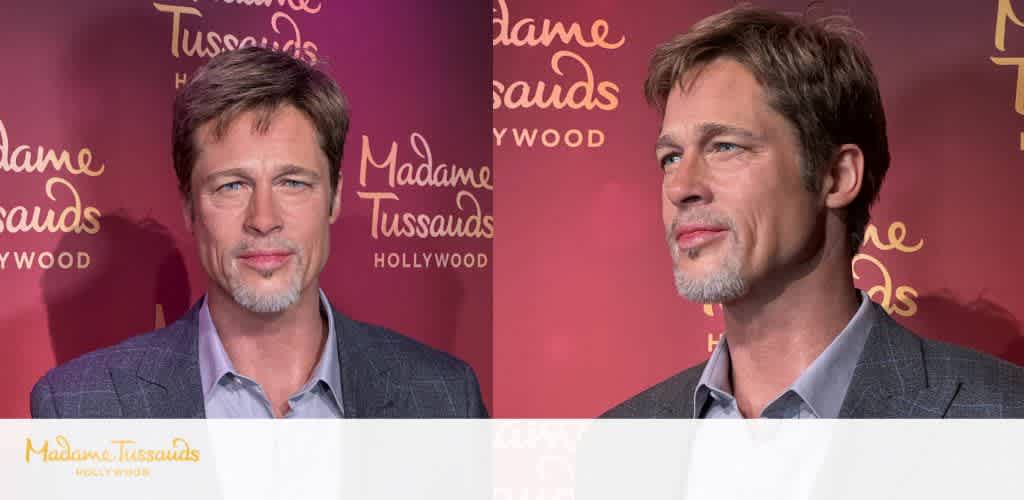 Photograph of a man with light brown hair and a beard, wearing a gray blazer and light shirt, standing in front of a Madam Tussauds Hollywood backdrop.
