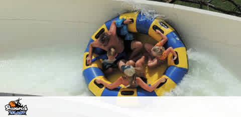 People in a raft slide down a water chute.