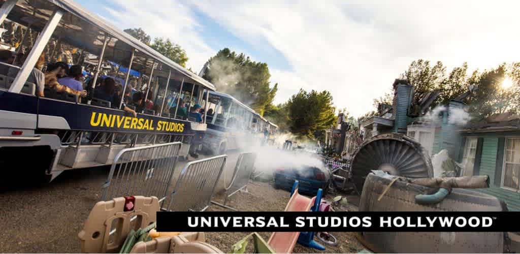 Experience the thrill of Universal Studios Hollywood on a studio tour tram. Visitors aboard the tram witness a staged special effects scene with smoke and overturned props, adding excitement to the outdoor adventure under a clear sky.