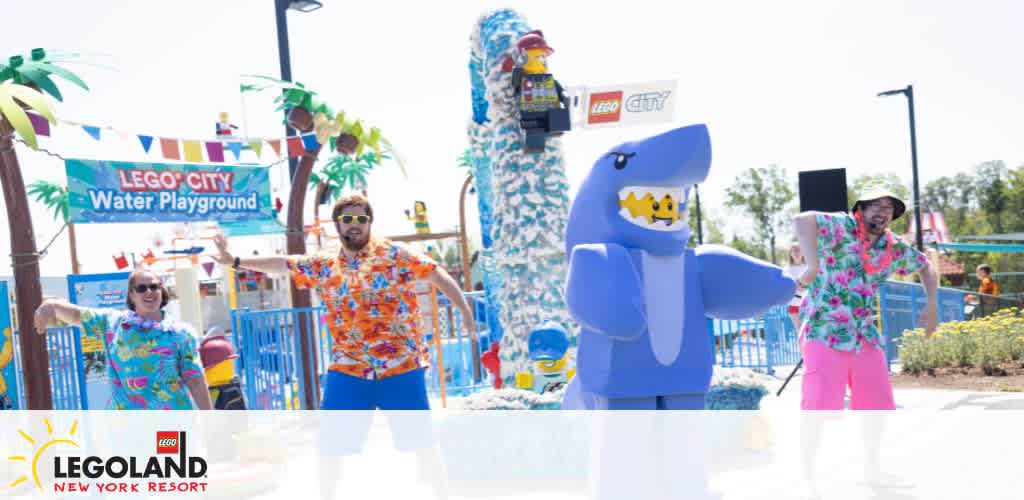 A bustling water play area at LEGOLAND New York Resort with children and adults enjoying various water features, slides, and LEGO-themed decorations on a sunny day.