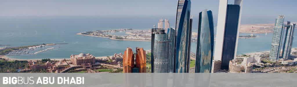 Panoramic view of Abu Dhabi skyline showcasing a blend of traditional and modern architecture. The left side features coastal and marina scenes with intricate buildings, while the right side exhibits a cluster of sleek, towering skyscrapers under a clear sky. In the foreground, the text BIGBUS ABU DHABI is overlaid.