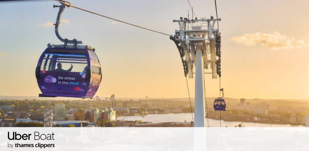 A scenic view of cable cars gliding over a cityscape at sunset. The sky is a warm golden hue, casting soft light over the landscape below. A message on one of the cable cars reads De-stress in the cloud. The river and buildings are visible in the background. The image includes logos for Uber Boat by Thames Clippers at the bottom.