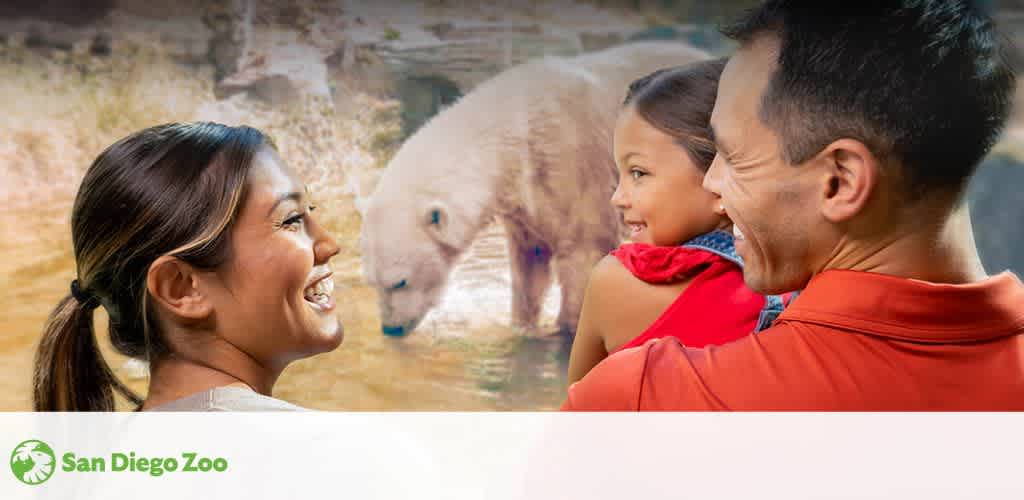 A family enjoys a day at the zoo, smiling and facing a polar bear in its enclosure. The bear stands in a shallow pool of water in a rocky habitat. The setting suggests a day filled with learning and fun at the zoo, where visitors can experience wildlife up close.