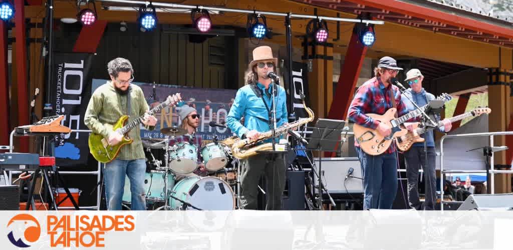 A band performs on an outdoor stage with various instruments and a canopy with hanging lights.