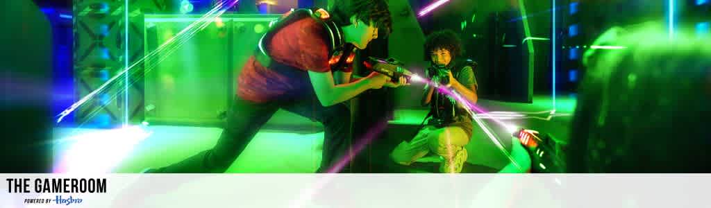 Two people play laser tag in a vibrant, neon-lit arena. They hold laser tag guns with determination, surrounded by glowing lights. The intense atmosphere suggests a competitive yet fun environment. Bright green and purple hues create an electric vibe.