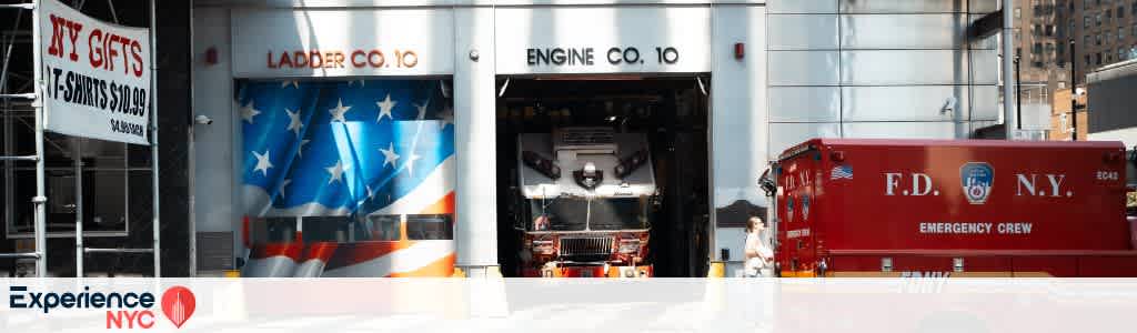 The image features a fire station in New York City with two garage doors marked Ladder Co. 10 and Engine Co. 10. A fire truck painted with an American flag design is visible. To the right, a red FDNY emergency vehicle is parked. A sign advertising NY gifts and T-shirts is on the left. The scene captures the vibrant and active environment of a city fire department.